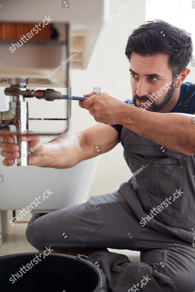 Plumber tightening a pipe fitting with a wrench