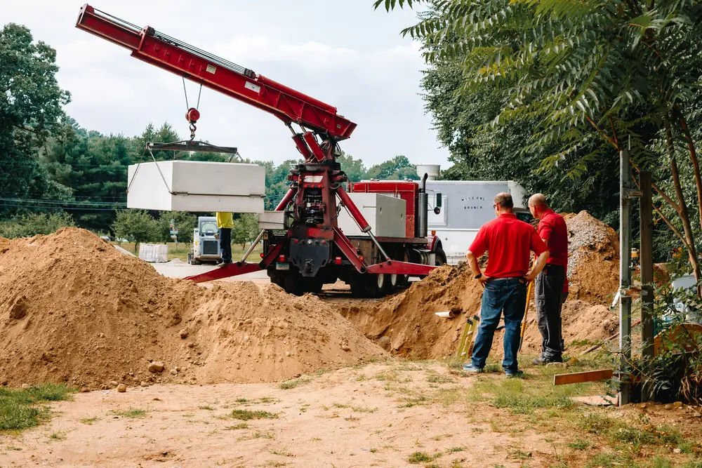 Crane truck lowering a new septic tank