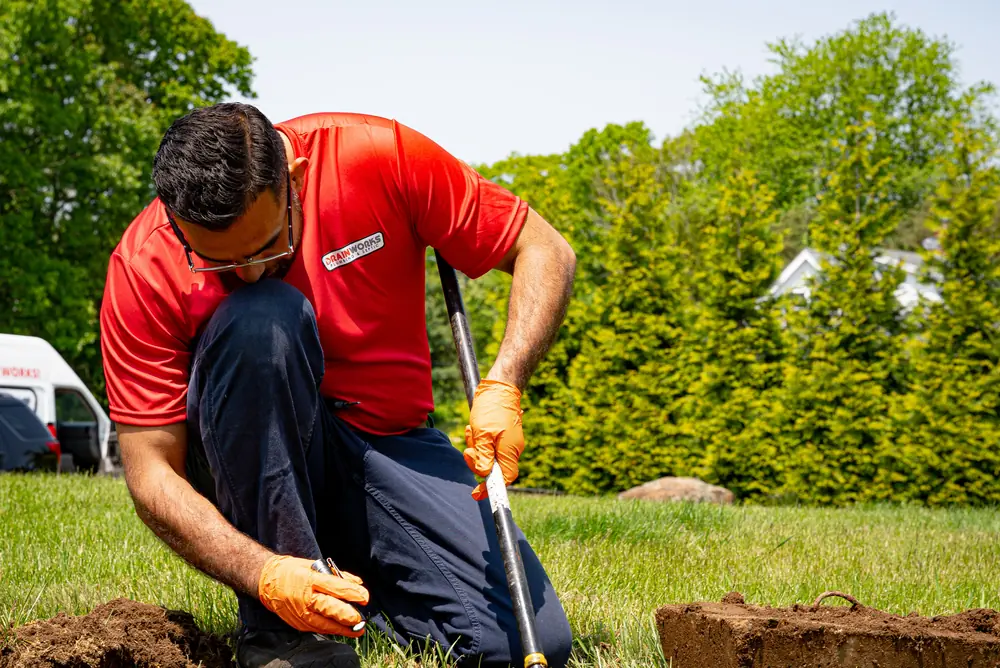 Drainworks technician probing a lawn to find the septic tank lids